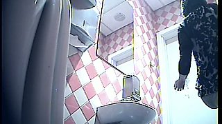 Brunette white lady in the public toilet room filmed from behind